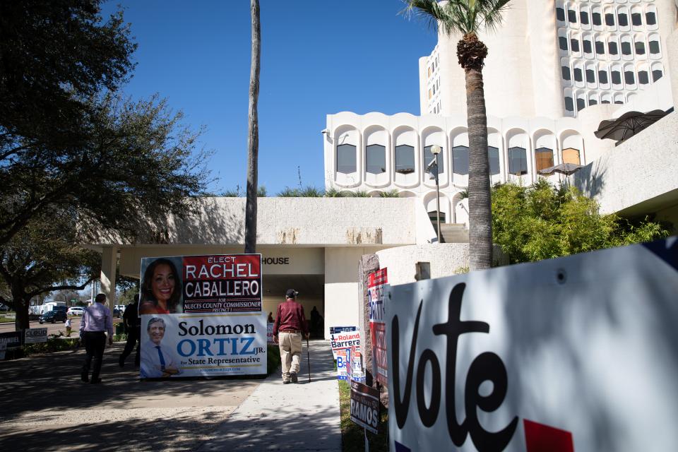 People walk past campaign signs linking the walkway to the Nueces County Courthouse, an early polling station, on Feb. 20, 2024, in Corpus Christi, Texas. Tuesday marked the first day of early voting for the Primary Election.