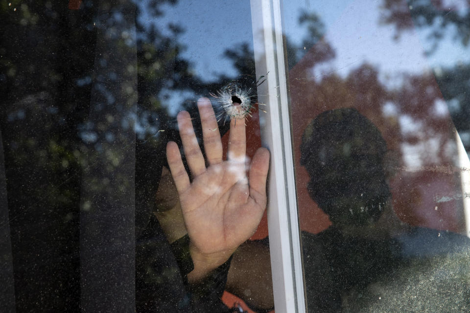 A police investigator inspects a gunshot hole at a home suspected of being a base for drug dealing in Rosario, Argentina, Thursday, Nov. 18, 2021. “Eighty percent of the crimes in Rosario are carried out by young hit men who provide services to drug gangs, whose bosses are imprisoned and maintain control of the criminal business from jails,” said Matías Edery, a prosecutor in the Organized Crime Unit in Santa Fe province. (AP Photo/Rodrigo Abd)