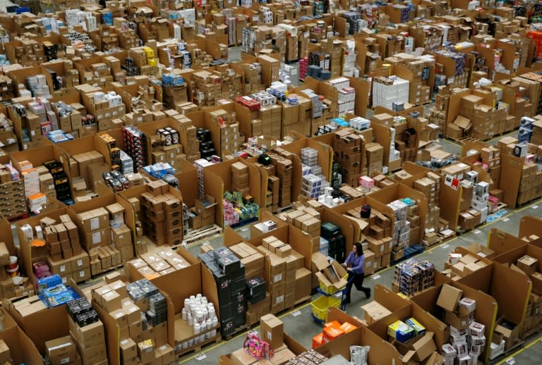 Workers walk along aisles of goods stored inside an Amazon.co.uk fulfillment centre in Hemel Hempstead, north of London, on November 25, 2015