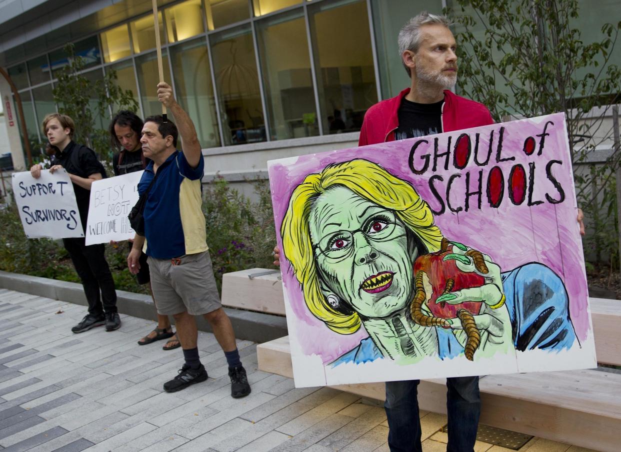A man protests Education Secretary Betsy DeVos at the dedication ceremony of Michigan State University's new Grand Rapids Medical Research Center: Cory Morse /The Grand Rapids Press via AP
