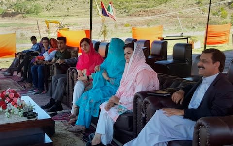 alala Yousafzai, center in red shawl, sits with her family members and Pakistan Information Minister Marriyum Aurangzeb, second right, during a visit to Swat Cadet College in Mingora - Credit: Abdullah Sherin/AP