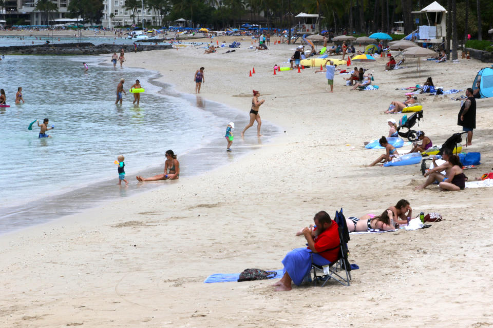 FILE — In this Aug. 24, 2021, file photo people sit on a Waikiki Beach in Honolulu. Hawaii was once seen as a beacon of safety during the pandemic because of stringent travel and quarantine restrictions and overall vaccine acceptance that made it one of the most inoculated states in the country. But the highly contagious delta variant exploited weaknesses and now the state is experiencing a record surge. (AP Photo/Caleb Jones, File)