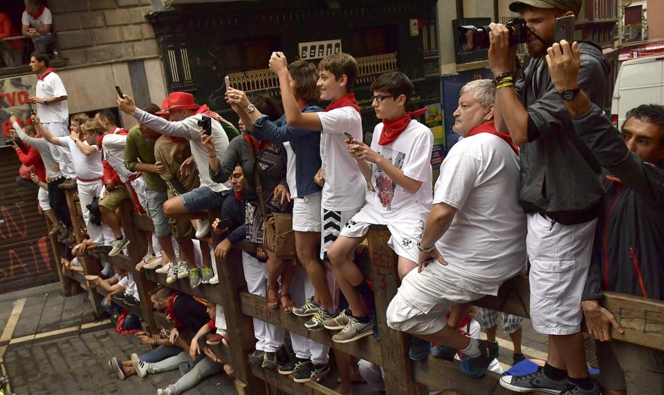 <p>People take photos as revellers run in front of Fuente Ymbro’s fighting bulls during the running of the bulls at the San Fermin Festival, in Pamplona, northern Spain, July 10, 2017. (AP Photo/Alvaro Barrientos) </p>