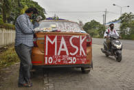 An Indian cab driver who has been out of work due to the COVID-19 pandemic, sells face masks from his car by a roadside in Kochi, Kerala state, India, Thursday, July 2, 2020. (AP Photo/R S Iyer)