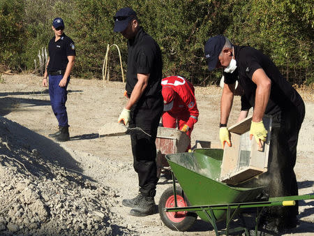 South Yorkshire police officers and members of the Greek rescue service (in red uniforms) investigate the ground while excavating a site during an investigation for Ben Needham, a 21-month-old British toddler who went missing in 1991, on the island of Kos, Greece, September 27, 2016. REUTERS/Vassilis Triandafyllou