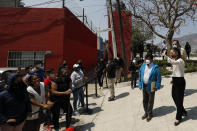 Mexico City Mayor Claudia Sheinbaum greets residents who gathered to watch from a distance during the inauguration of a new aerial public transit system dubbed the Cablebus, in the Cuautepec neighborhood of northern Mexico City, Thursday, March 4, 2021. For the residents of Cuautepec, this new system, the first of four planned lines, will turn a commute to the nearest subway station, that can last up to two hours, into a 30-minute ride. (AP Photo/Rebecca Blackwell)