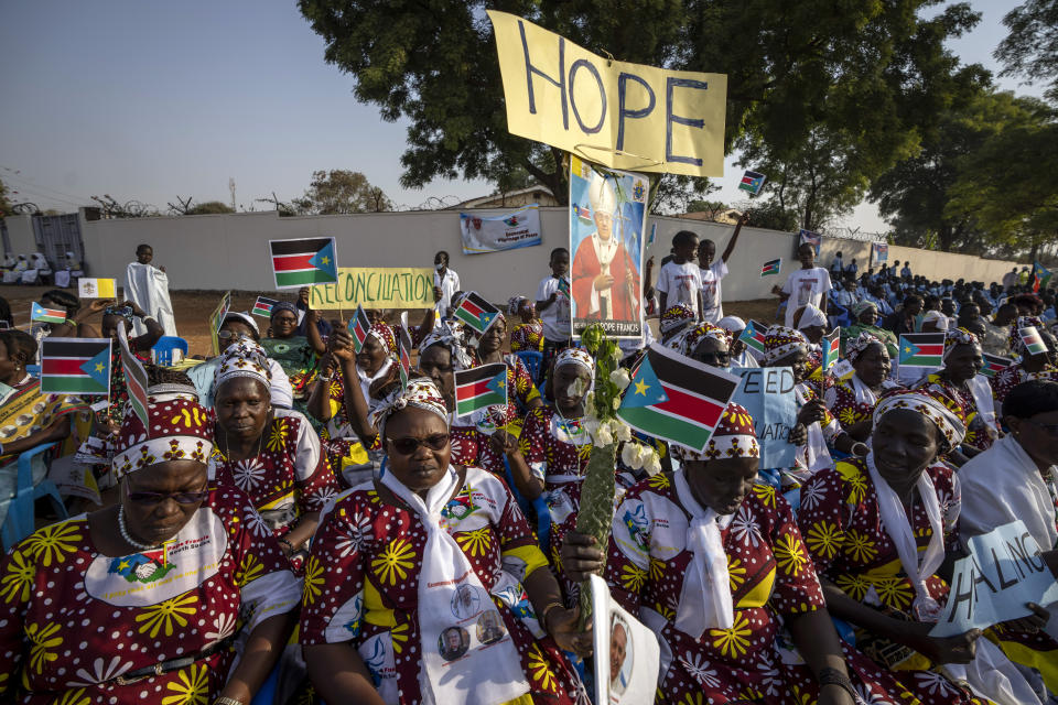 Women holding national flags and peace banners await the arrival of Pope Francis at the St. Theresa Cathedral in Juba, South Sudan Saturday, Feb. 4, 2023. Pope Francis is in South Sudan on the second leg of a six-day trip that started in Congo, hoping to bring comfort and encouragement to two countries that have been riven by poverty, conflicts and what he calls a "colonialist mentality" that has exploited Africa for centuries. (AP Photo/Ben Curtis)