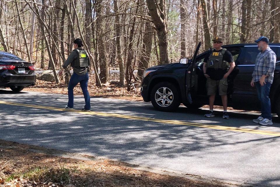 An FBI negotiator vest walks on a road in North Dighton, Mass., on April 13, 2023. The person at the center of the massive leak of internal classified documents from the Pentagon has been identified as a 21-year-old Massachusetts Air National Guardsman.