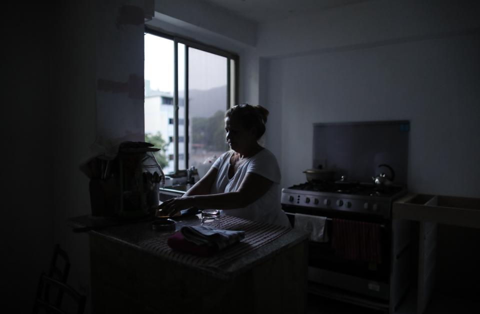 Orelis Lehmann gets ready to make coffee in her darkened apartment in Caracas, Venezuela, Tuesday, July 23, 2019. In neighborhoods like Santa Monica where the Lehmann's building stands, the darkness lingered even as other parts of Caracas began springing back to life Tuesday. (AP Photo/Ariana Cubillos)