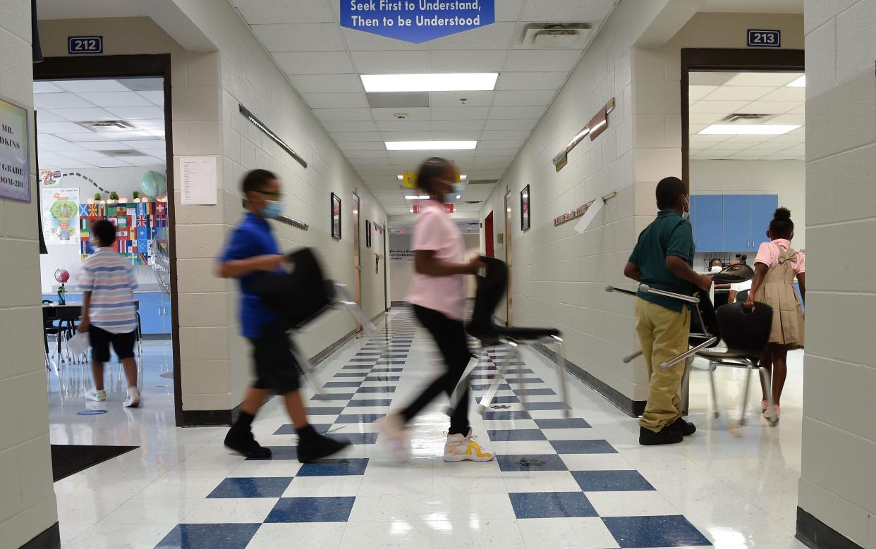 Kellie Marks's students move to another classroom with their chairs in hand at Napier Elementary School in Nashville, Tenn., Tuesday, Aug. 10, 2021. 