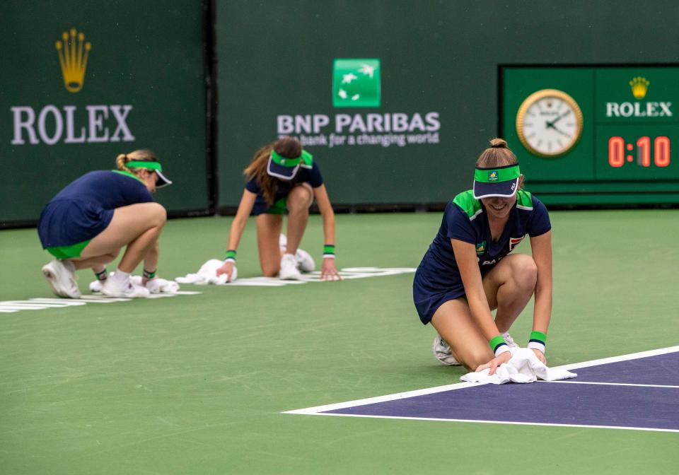 Members of the ball crew wipe down the lines as the rain lets up after the first rain break during Maria Sakkari and Shelby Rogers' second-round match at the BNP Paribas Open at the Indian Wells Tennis Garden in Indian Wells, Calif., Friday, March 10, 2023. 