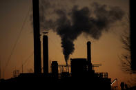 FILE - In this Friday, Dec. 14, 2018 filer, smoke billows from a chimney of a factory, in Ospiate, near Milan, Italy. The eurozone's third-largest economy and a major exporter, Italy on Wednesday becomes the first western industrialized nation to idle swaths of industrial production to stop the spread of coronavirus by keeping yet more of the population at home. The new coronavirus causes mild or moderate symptoms for most people, but for some, especially older adults and people with existing health problems, it can cause more severe illness or death. (AP Photo/Luca Bruno, File)