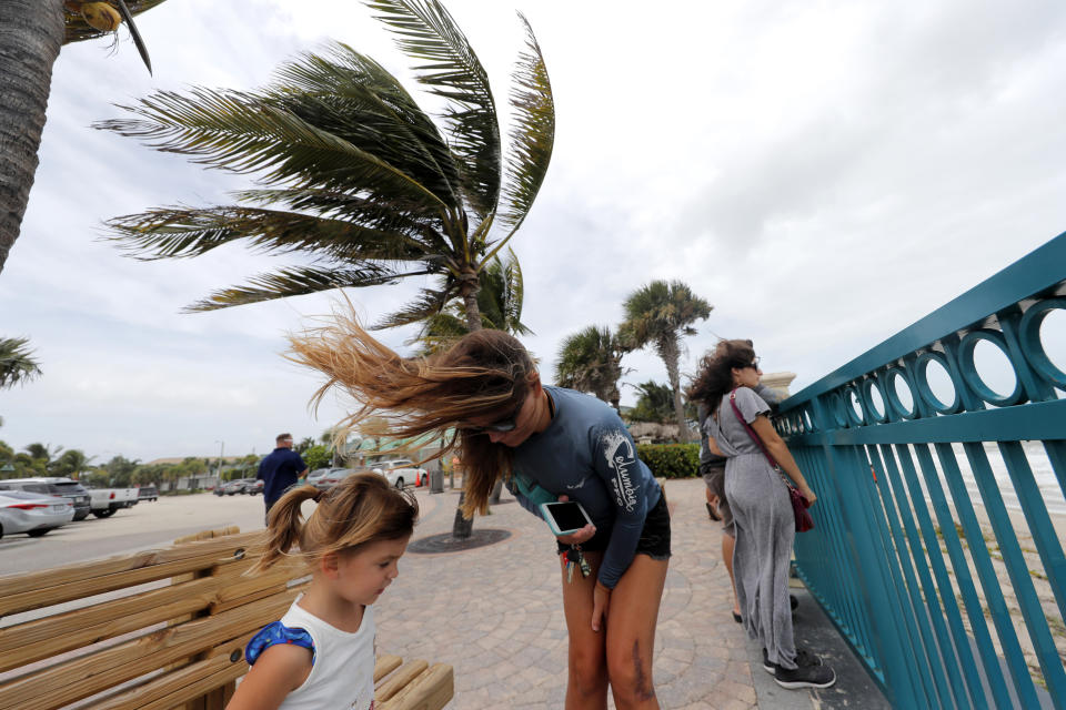 Kristen Davis watches the high surf from a boardwalk overlooking the Atlantic Ocean with her daughter Addie Davis, 4, as winds from Hurricane Dorian blow the fronds of a palm tree in Vero Beach, Fla., Monday, Sept. 2, 2019. (AP Photo/Gerald Herbert)