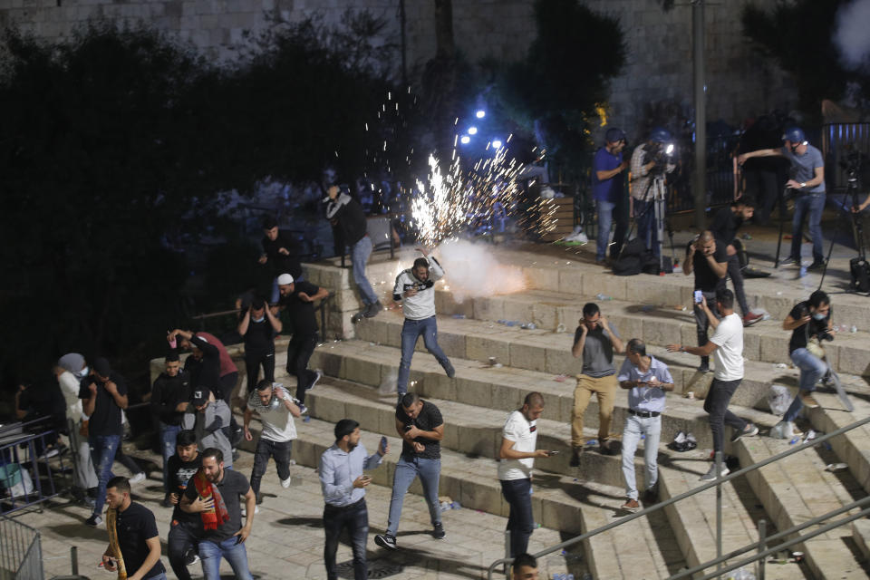 Palestinians run from stun grenades fired by Israeli police officers during clashes at Damascus Gate just outside Jerusalem's Old City, Saturday, May 8, 2021. Israeli police on Saturday clashed with Palestinian protesters outside Jerusalem's Old City during the holiest night of Ramadan, in a show of force that threatened to deepen the holy city's worst religious unrest in several years. (AP Photo/Oded Balilty)