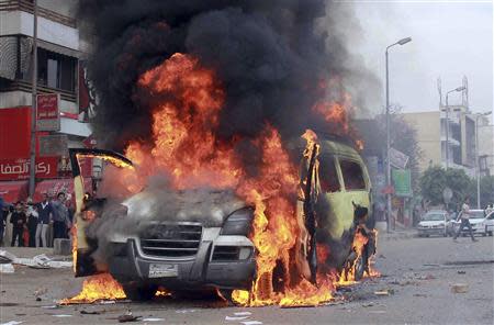 Smoke rises as protesters, supporters of ousted President Mohamed Mursi, burn the car of independent television channel Al-Tahrir TV, during clashes with police in al-Haram street, south of Cairo, February 21, 2014. REUTERS/Al Youm Al Saabi Newspaper