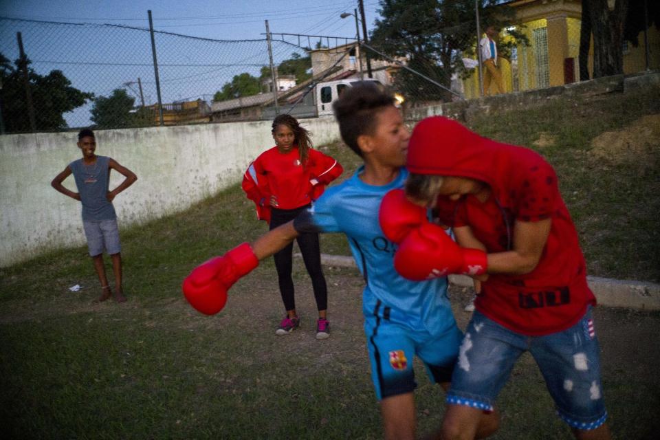 In this Jan. 19, 2017 photo, boxer Idamelys Moreno, center back, looks at children playing around, at a sports center in Havana, Cuba. Boxing has long been an athletic engine for Cuba, which has won 72 Olympic medals in that category but women are not allowed to box. (AP Photo/Ramon Espinosa)