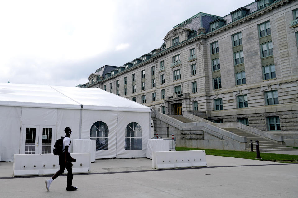 A midshipman wears a face mask to protect against COVID-19 while walking near a tent set up as a social distant mess hall on the grounds of the U.S. Naval Academy, Monday, Aug. 24, 2020, in Annapolis, Md. Under the siege of the coronavirus pandemic, classes have begun at the Naval Academy, the Air Force Academy and the U.S. Military Academy at West Point. But unlike at many colleges around the country, most students are on campus and many will attend classes in person. (AP Photo/Julio Cortez)