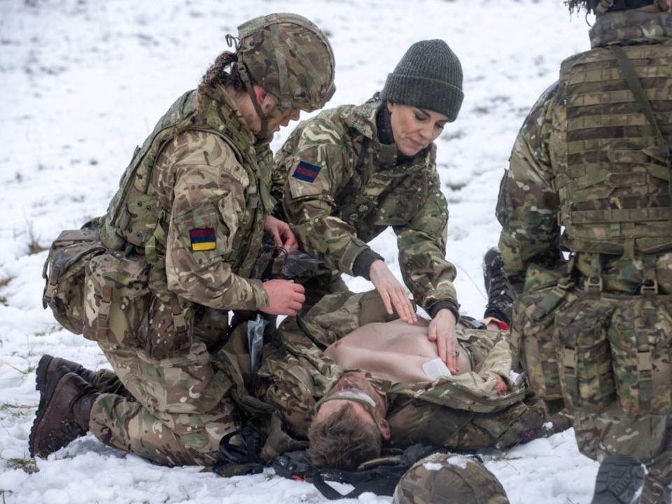 Kate Middleton kneels down in the snow during a training exercise.