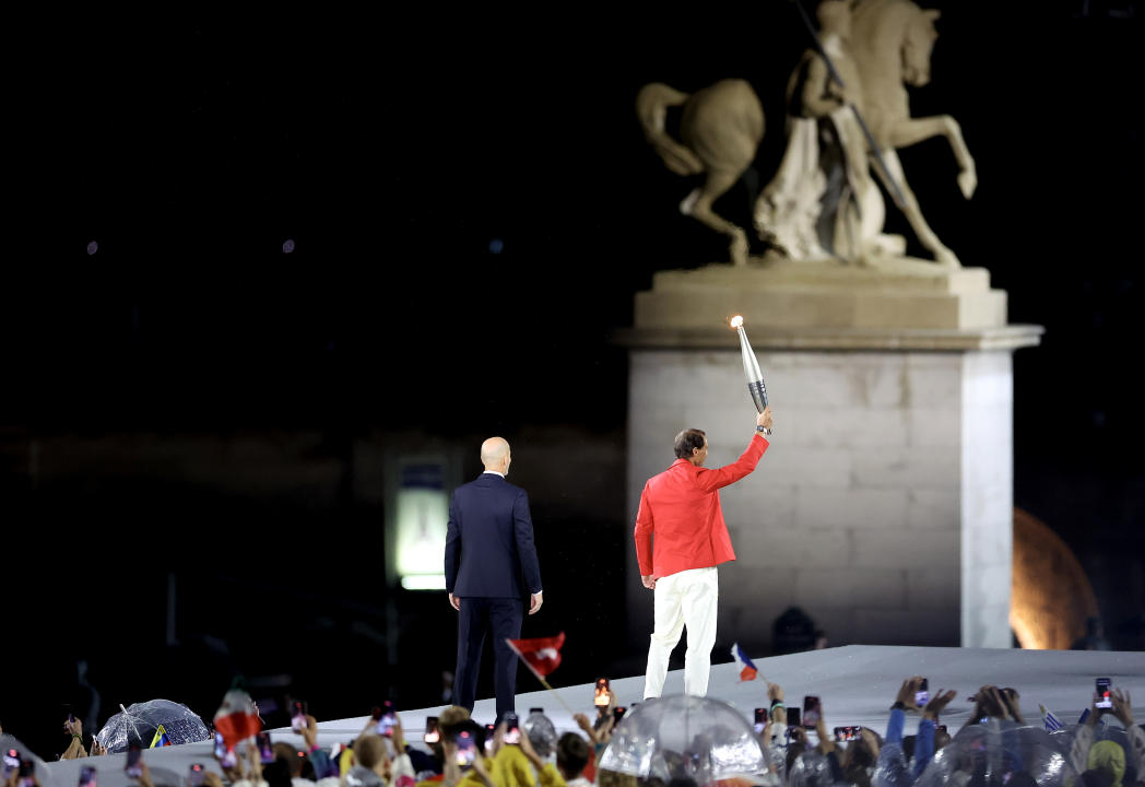 PARIS, FRANCE - JULY 26: Tennis Player Rafael Nadal of Team Spain receives the Olympic Torch from Former French Footballer Zinedine Zidane during the opening ceremony of the Olympic Games Paris 2024 on July 26, 2024 in Paris, France. (Photo by Hector Vivas/Getty Images)