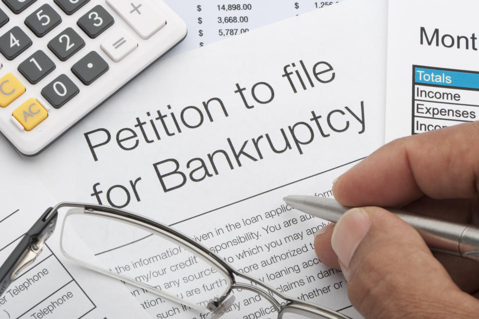 Close up of bankruptcy petition with calculator and writing hand