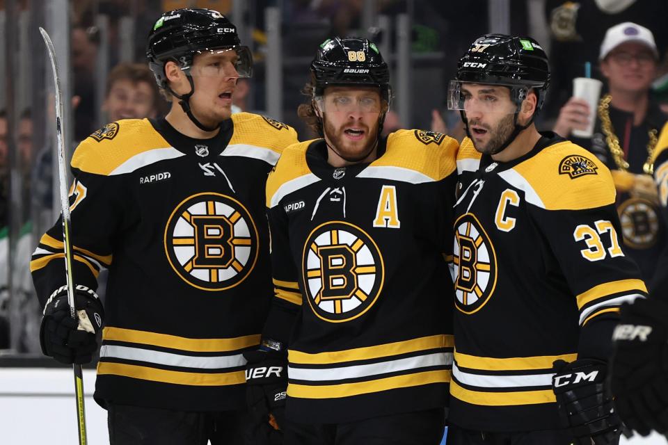 BOSTON, MASSACHUSETTS - OCTOBER 25: David Pastrnak #88 of the Boston Bruins celebrates with Hampus Lindholm #27 and Patrice Bergeron #37 after scoring a goal against the Dallas Stars during the first period at TD Garden on October 25, 2022 in Boston, Massachusetts. (Photo by Maddie Meyer/Getty Images)