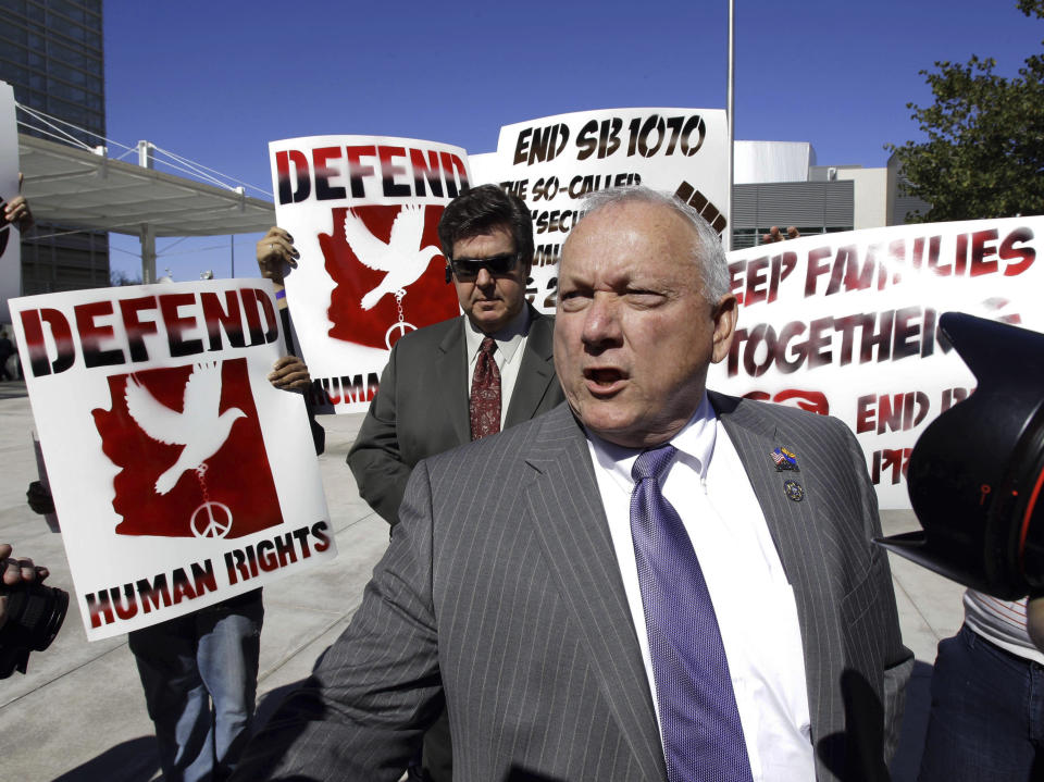 FILE - Protestors gather around Arizona State Sen. Russell Pearce, R-Mesa, author of Arizona's immigration bill SB1070, outside the Sandra Day O'Connor Federal Courthouse on Feb. 10, 2011, in Phoenix. Pearce, a Republican lawmaker who was the driving force behind Arizona's landmark 2010 immigration legislation known as the “show me your papers” law and other anti-immigrant measures, has died Thursday, Jan. 5, 2023. He was 75. (AP Photo/Matt York, File)