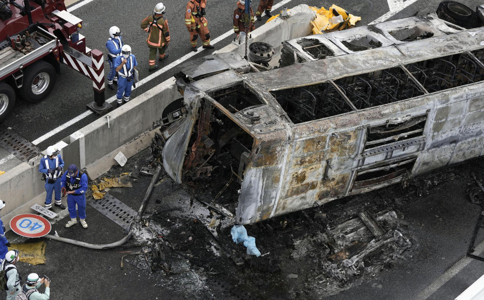 Investigators work near the overturned bus on a high way in Toyoyama, Aichi prefecture, central Japan Monday, Aug. 22, 2022. A passenger bus crashed into a dividing strip, overturned to its side and caught fire on an expressway in central Japan on Monday, leaving two people burned to death and slightly injuring seven others, police said. (Kyodo News via AP)