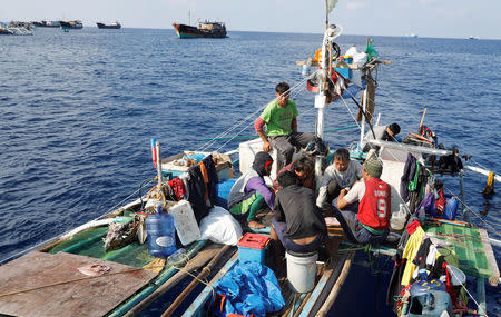 Filipino fishermen eat a meal aboard a fishing boat overlooking Chinese fishing vessels at the disputed Scarborough Shoal April 6, 2017. Picture taken April 6, 2017 REUTERS/Erik De Castro