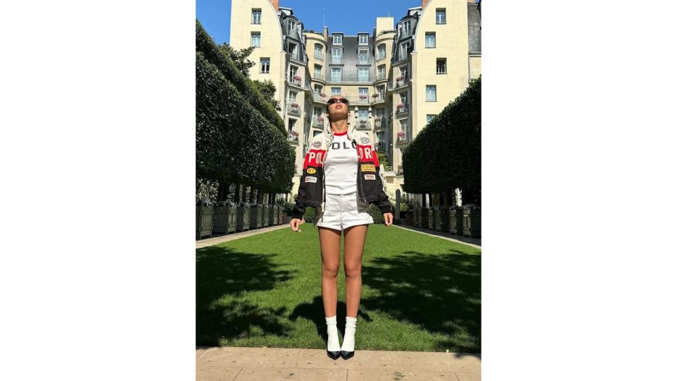 Emma Chamberlain poses in white shorts and a motorcycle jacket at the Olympic Games