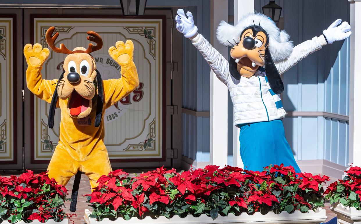 Dressed in their holiday outfits, Pluto and Goofy pose for a photo along Main Street in Disneyland on Saturday, November 13, 2021, in Anaheim.