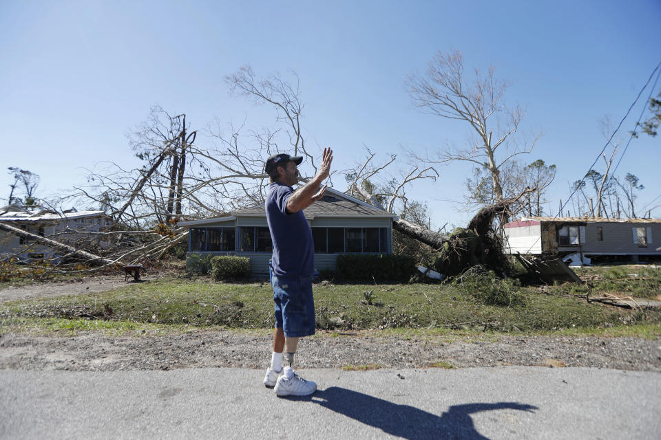 In this Oct. 13, 2018 photo, Clinton Moseley who lives with his mother, stands in front of her home after a tree fell on the home during Hurricane Michael, in Panama City, Fla. The house has been in his family for a century. Water gushed in, but he said they’re staying. (AP Photo/Gerald Herbert)