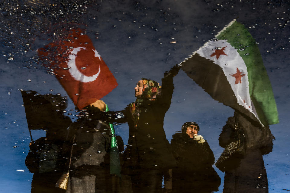 A reflection shows a woman waving Turkish and Free Syrian flags as an aid convoy to Aleppo organized by IHH Humanitarian Relief Foundation is about to leave, on Dec. 14, 2016 in Istanbul.