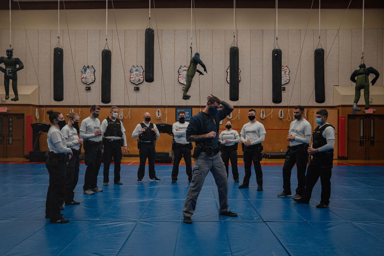 With punching bags and dummies overhead, instructor Javier Sola teaches frisking and handcuffing methods to police recruits at the Washington State Criminal Justice Training Commission facility in Burien, Wash., on Oct. 22. Washington State requires all new recruits to go through the state-run Basic Law Enforcement Academy, except for those becoming state patrol officers.