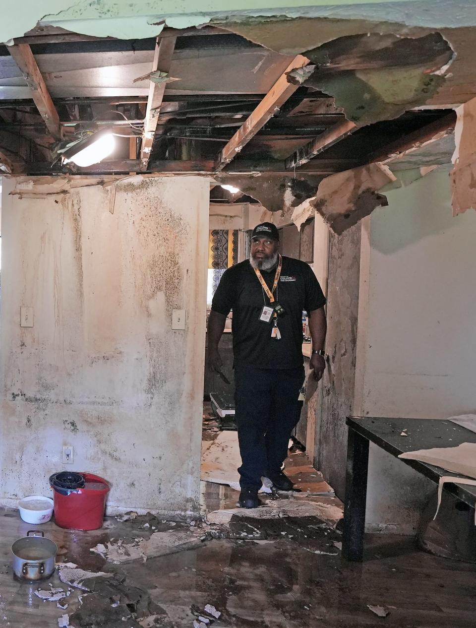 City of Columbus property maintenance inspector Cliffort Turner (right) looks at the water damage inside Aydarus Farah's Carriage House apartments on Innis Road on the Northeast Side. Farah, 73, said he reported the damage for weeks but it had not been repaired.