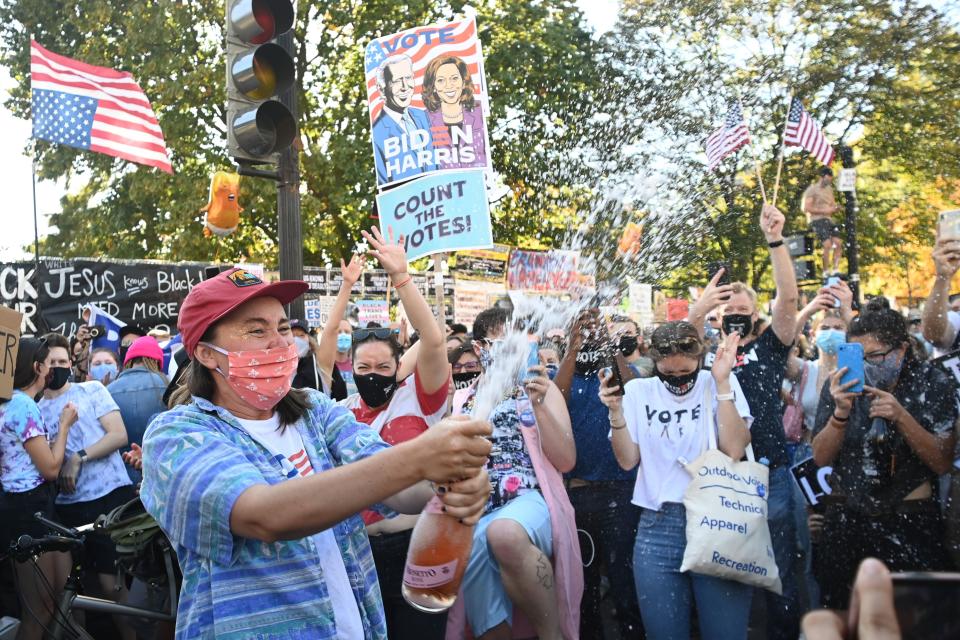 <p>A woman sprays prosecco onto the crowd as people celebrate on Black Lives Matter plaza across from the White House in Washington, DC</p>AFP via Getty Images