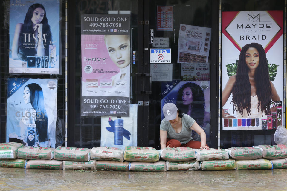A shop owner piles sandbags around the entrance as street flooding approaches the building after Hurricane Beryl moved through Monday, July 8, 2024, in Galveston, Texas. (AP Photo/Michael Wyke)