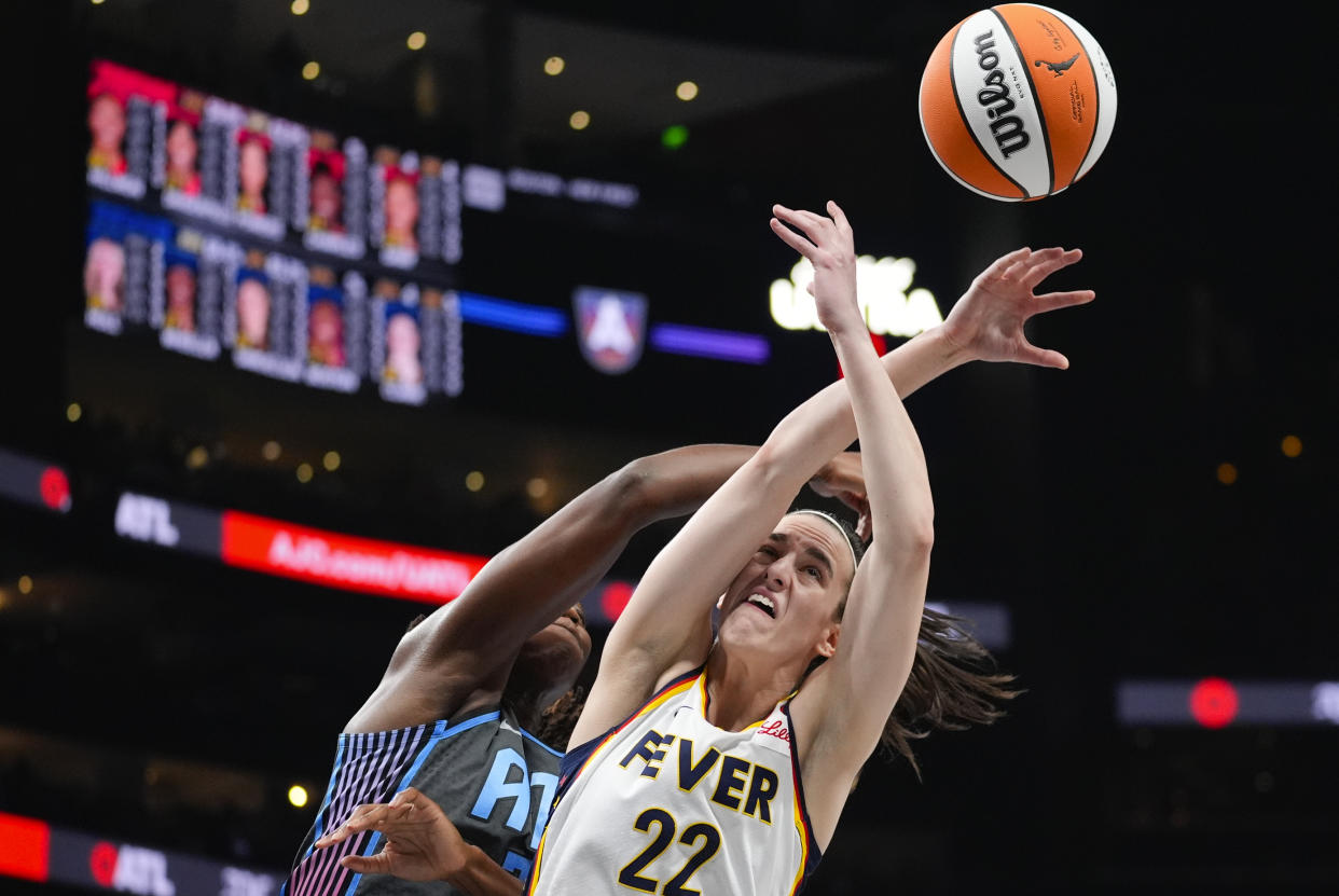 Indiana Fever guard Caitlin Clark (22) battles Atlanta Dream center Tina Charles for a rebound during the first half of a WNBA basketball game Friday, June 21, 2024, in Atlanta. (AP Photo/John Bazemore)