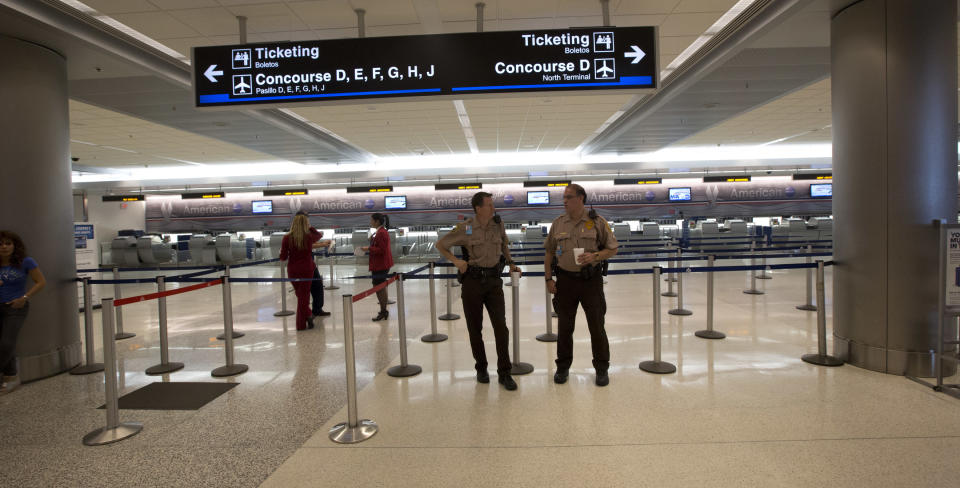 Police officers guard an empty check-in area at the American Airlines section of the Miami International Airport, Tuesday, April 16, 2013. American Airlines says it has fixed an outage in its main reservations system that is disrupting travel for thousands of passengers whose flights have been delayed or canceled. But the airline expects to see flight delays and cancellations throughout the rest of the day. (AP Photo/J Pat Carter)