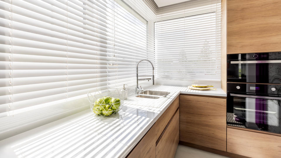 A modern kitchen with the blinds closed in the windows