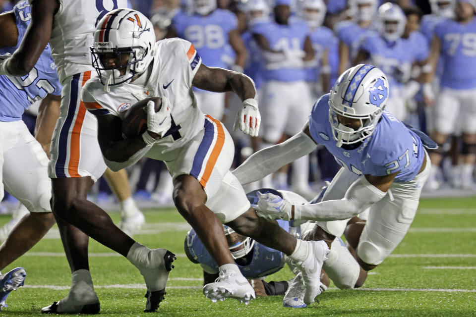Virginia wide receiver Malik Washington (4) avoids a tackle by North Carolina defensive back Giovanni Biggers (27) as he runs for a touchdown during the second half of an NCAA college football game, Saturday, Oct. 21, 2023, in Chapel Hill, N.C. (AP Photo/Chris Seward)