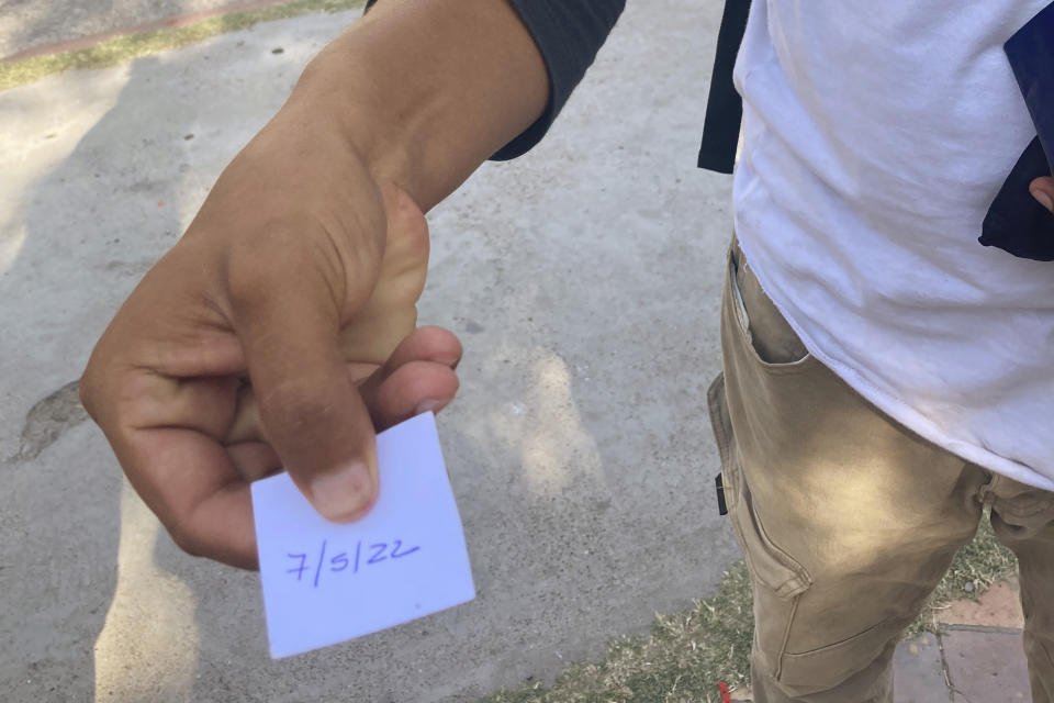 On May 21, 2022, a migrant displays an appointment slip to be interviewed at Casa del Migrante migrant services center on May 7, 2022 for possible entry to the United States. The interview was canceled after overwhelming demand. (AP Photo/Elliot Spagat)