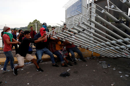 A group of men, part of a caravan of thousands of migrants from Central America en route to the U.S., pull down the border gate with the intention to carry on their journey, in Tecun Uman, Guatemala, October 28, 2018. REUTERS/Carlos Garcia Rawlins/File photo