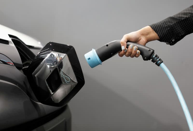 FOTO DE ARCHIVO. Una mujer sostiene un cable para cargar un vehículo utilitario eléctrico Renault Kangoo ZE en un concesionario de Renault en Cagnes-Sur-Mer, Francia