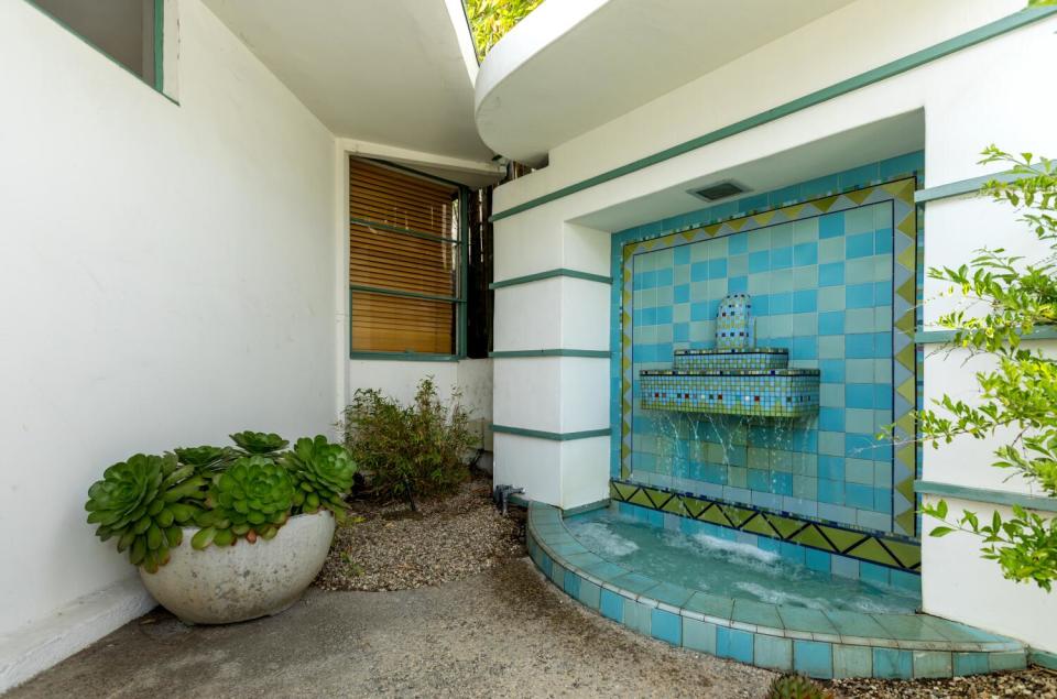 A potted plant next to a blue tiled fountain.