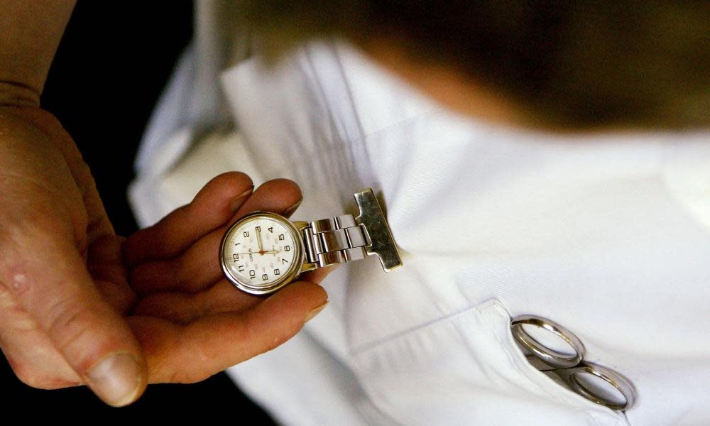 A nurse checks his fob watch