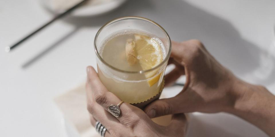 woman holding glass of ginger lemon tea