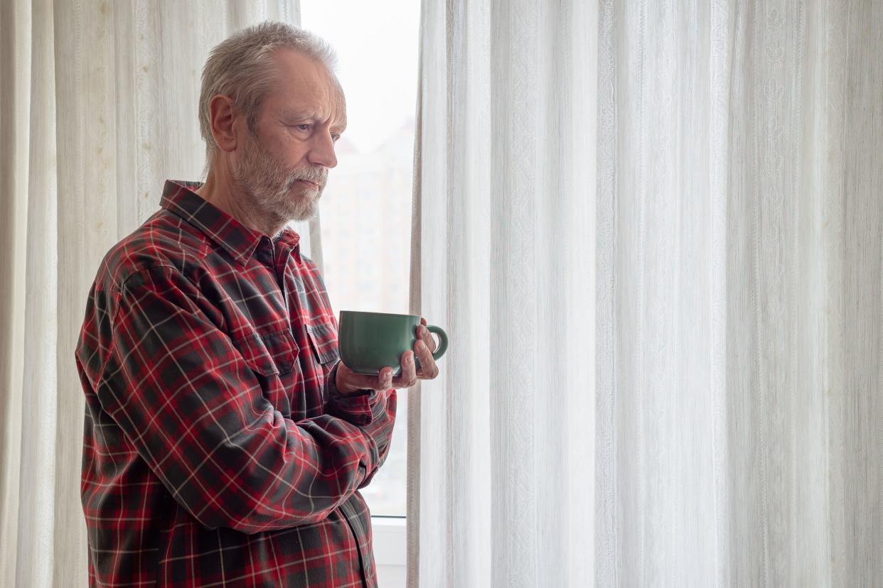 thoughtful mature man drinking his coffee and looking out of the window