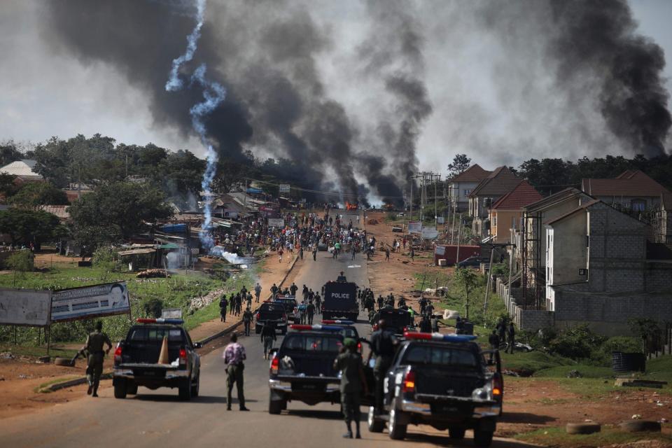 Nigerian Police fire teargas at people during clashes between youths in Apo, Abuja, Nigeria - AFP