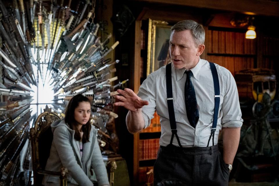 Daniel Craig and Ana de Armas in a still from Knives Out, Craig gesturing in a vintage room