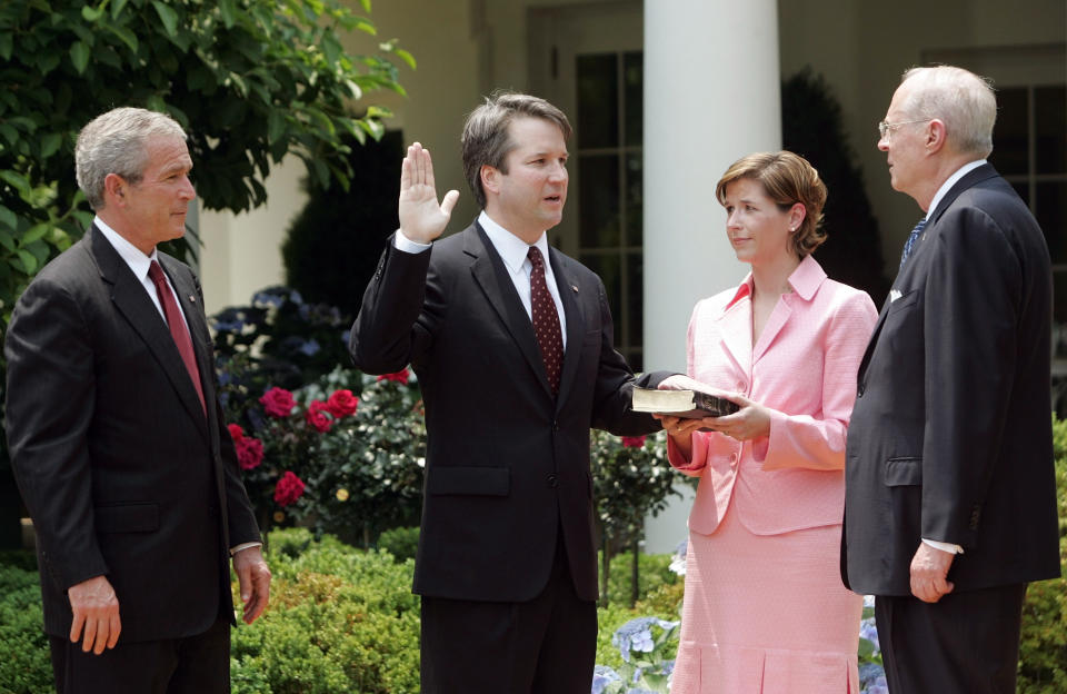 FILE - In this June 1, 2006 file photo, from left to right, President Bush, watches the swearing-in of Brett Kavanaugh as Judge for the U.S. Court of Appeals for the District of Columbia by U.S. Supreme Court Associate Justice Anthony M. Kennedy, far right, during a ceremony in the Rose Garden of the White House, in Washington. Holding the Bible is Kavanaugh's wife Ashley Kavanaugh. Kavanaugh has been a conservative team player, and the Supreme Court nominee has stepped up to make a play at key moments in politics, government and the law dating to the Bill Clinton era. (AP Photo/Pablo Martinez Monsivais, File)